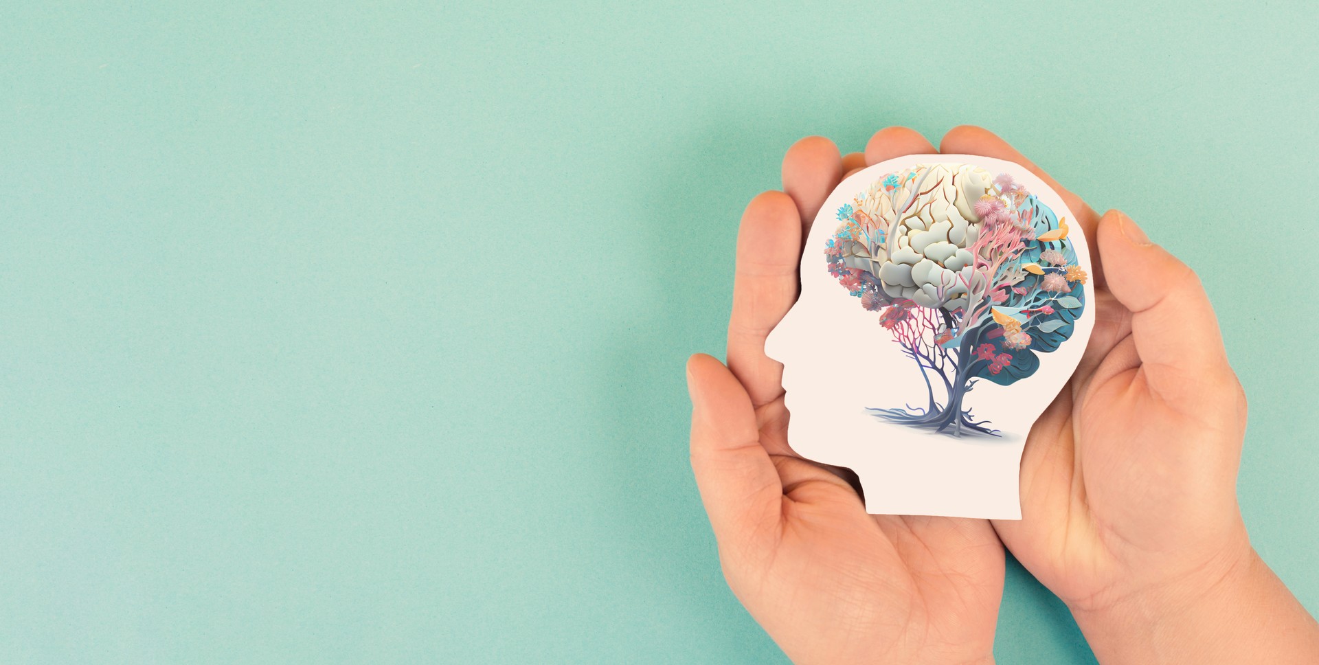 Hands holding paper head, human brain with flowers, self care and mental health concept, positive thinking, creative mind