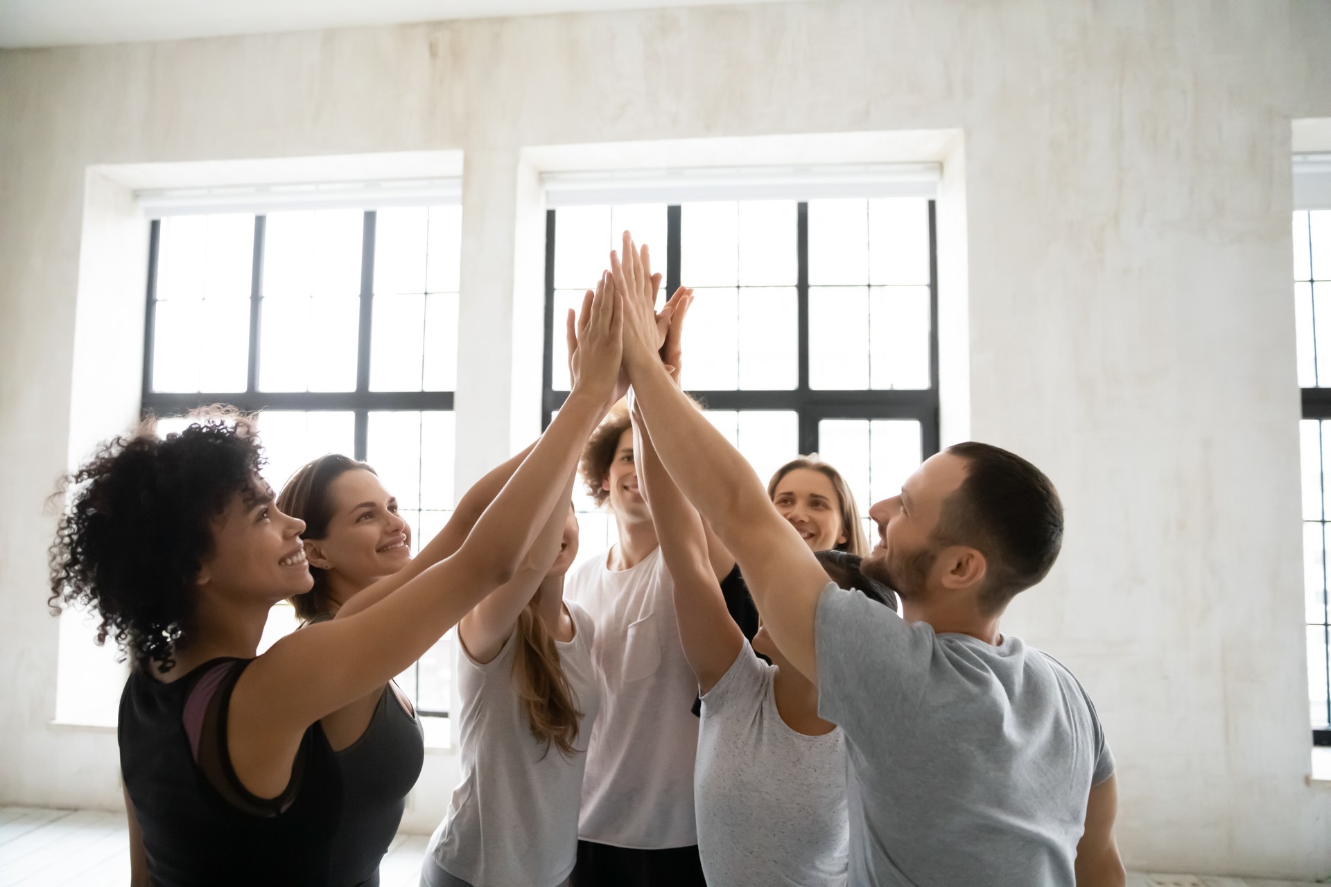 Happy smiling diverse people sharing success, giving high five